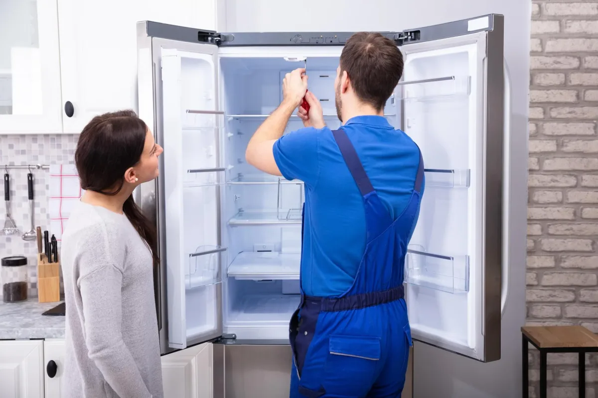 Kühlschrank Reparatur Wien - Techniker repariert Kühlschrank beim Kunden